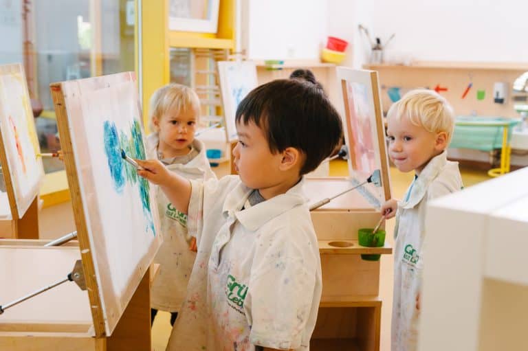 Kind malt mit Pinsel an der Staffelei