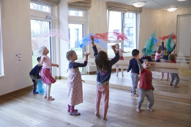 Kinder tanzen mit bunten Tüchern vor Spiegelwand