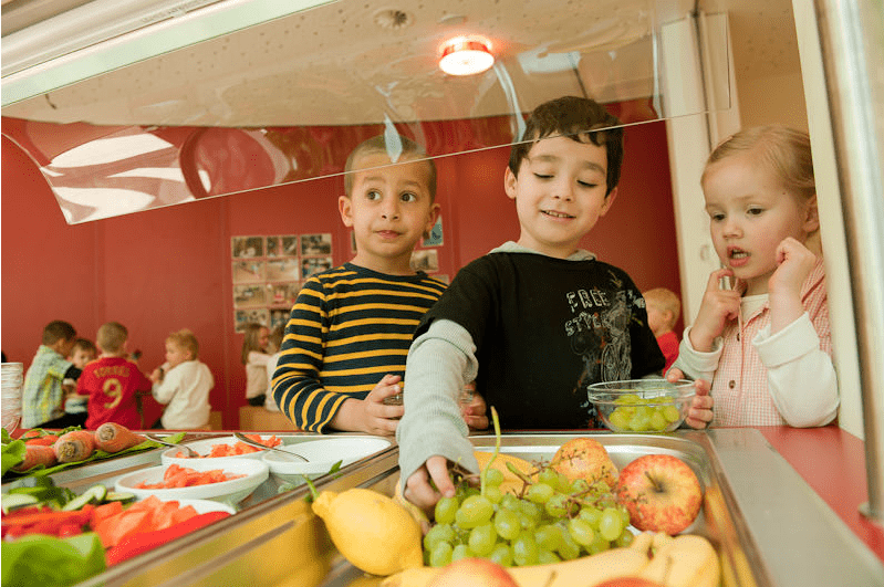 Kinder nehmen Obst vom Buffet