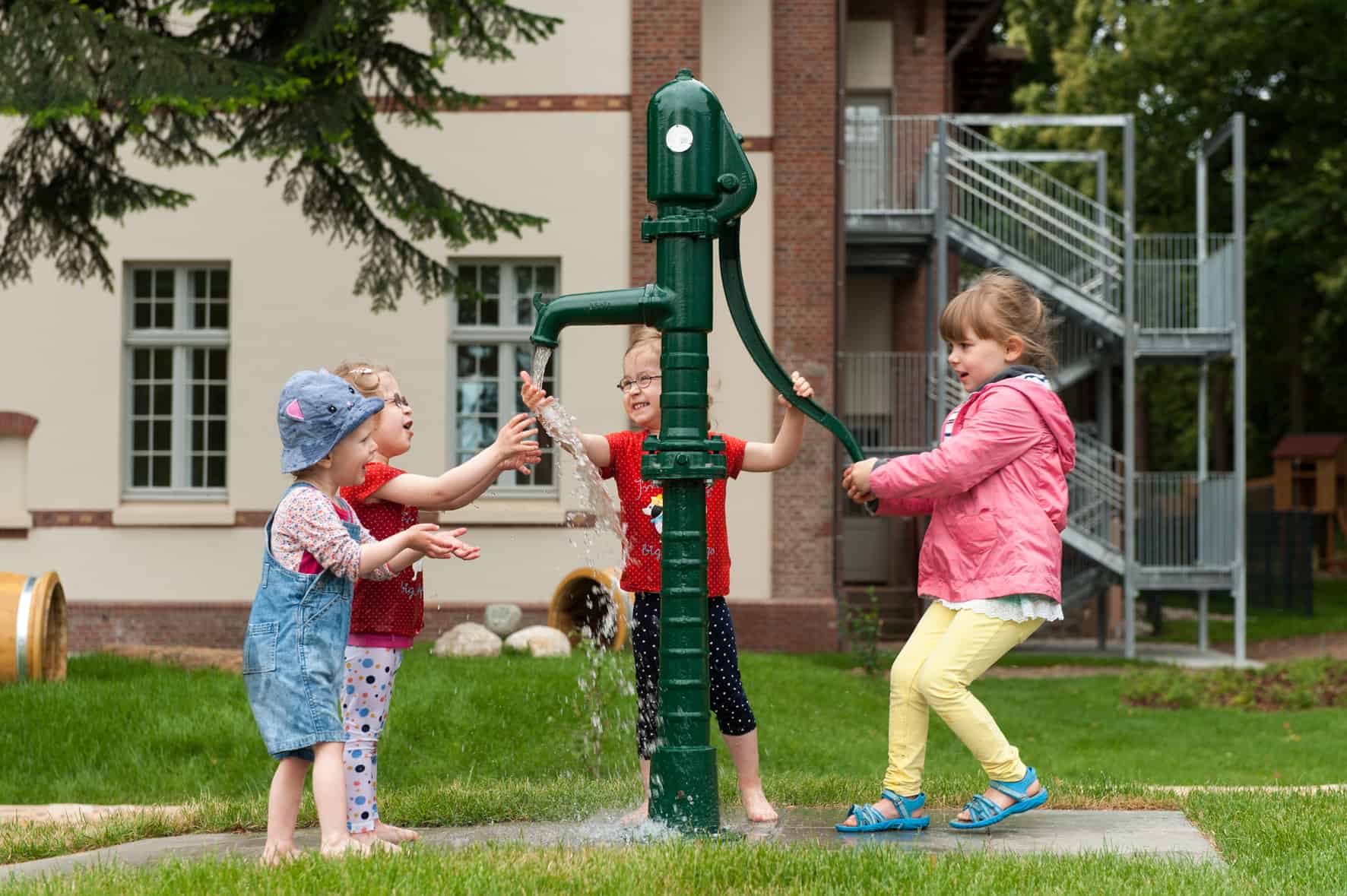 Kinder spielen an der Wasserpumpe im Außenbereich