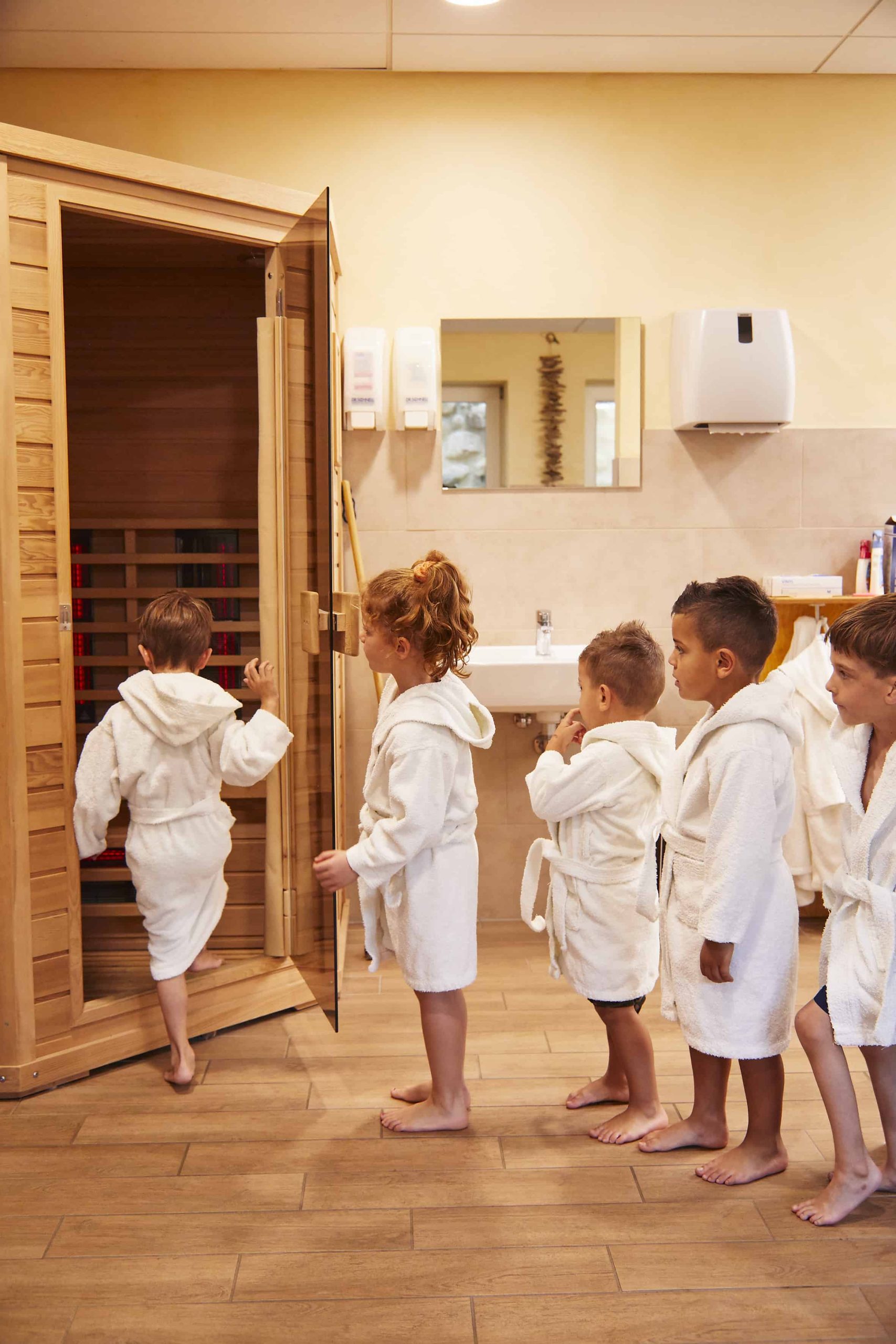 Kinder mit Bademänteln betreten die Sauna