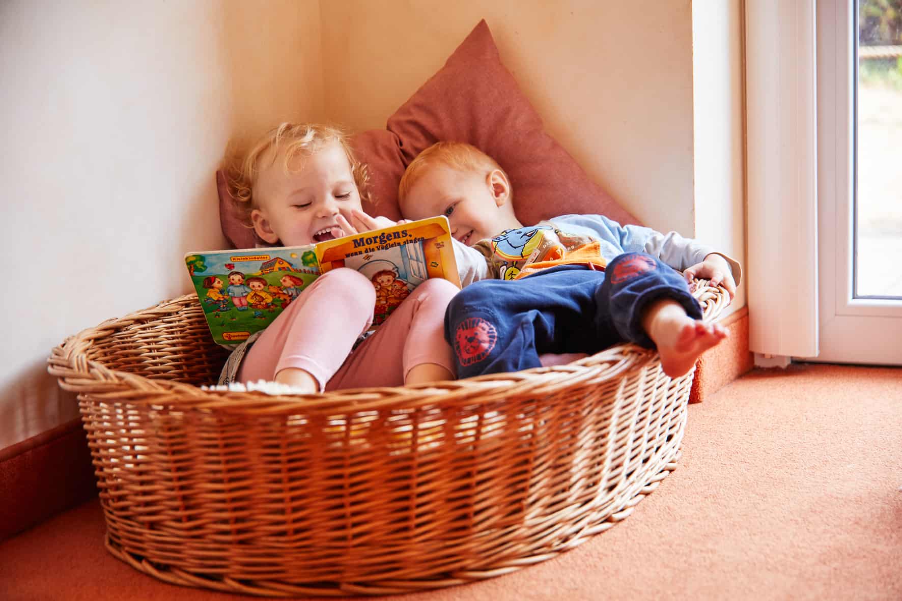 Kinder kuscheln auf einem Kissen und lesen ein Buch