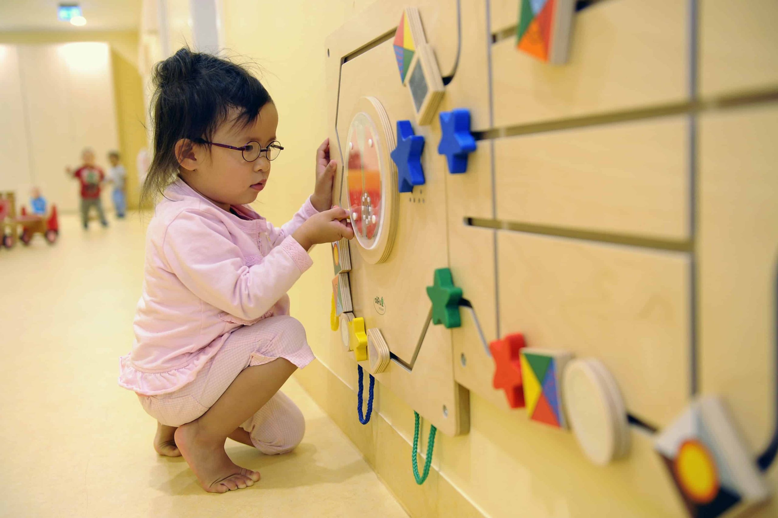 Kind spielt an Schiebeelementen an der Wand