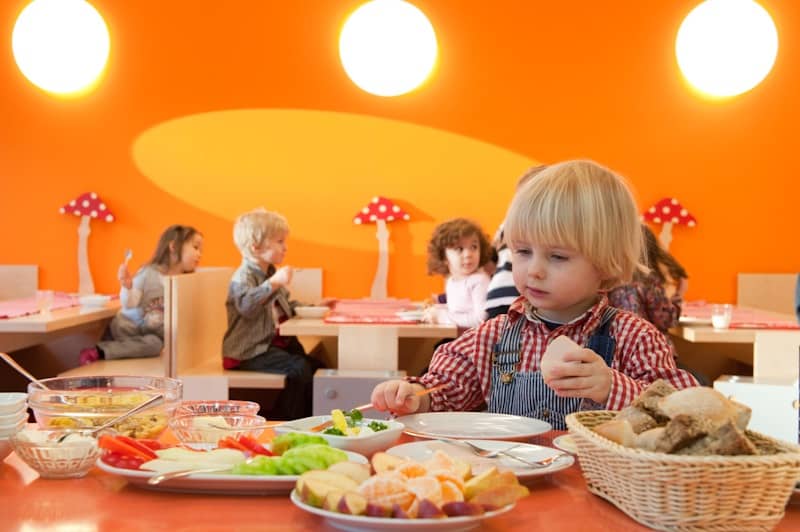 Kind am Frühstücksbuffet mit Obst und Gemüse