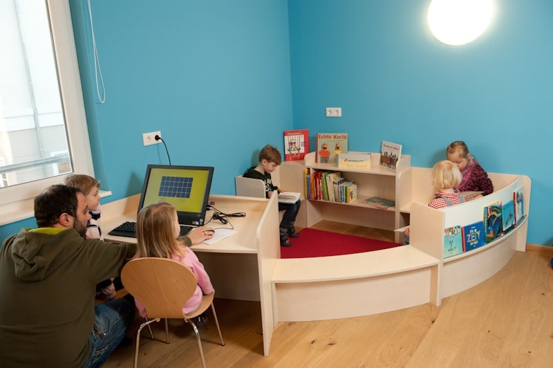 Kinder mit Bilderbüchern und am Computer in der Bibliothek