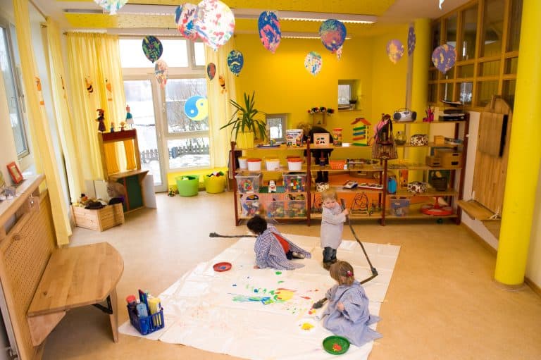 Kinder bemalen großes Laken auf dem Boden im Atelier