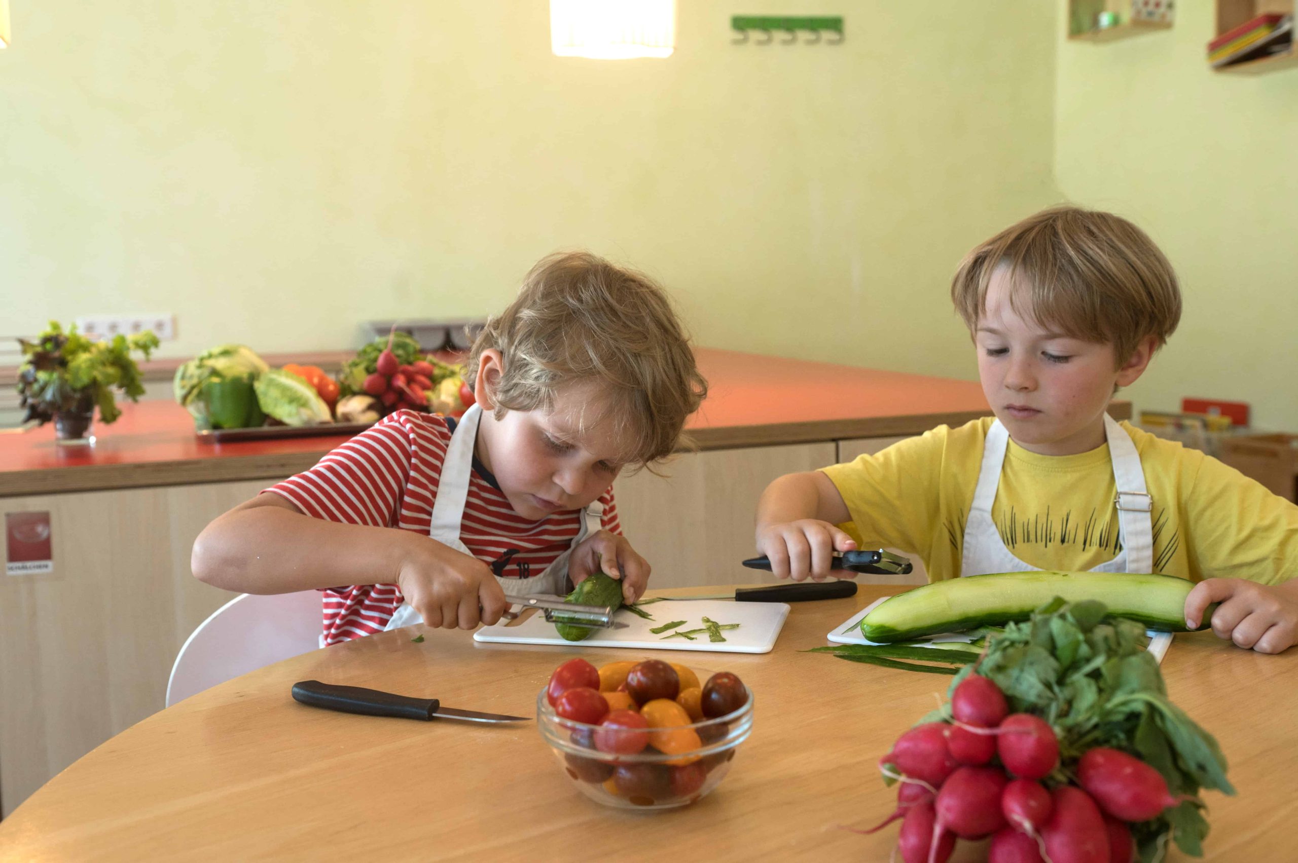 Kinder schneiden Gemüse in der Kinderküche