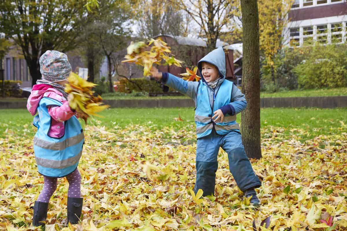 Kinder bewerfen sich mit Herbstlaub